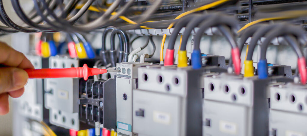 Électricien testant la tension et le courant sur un tableau électrique